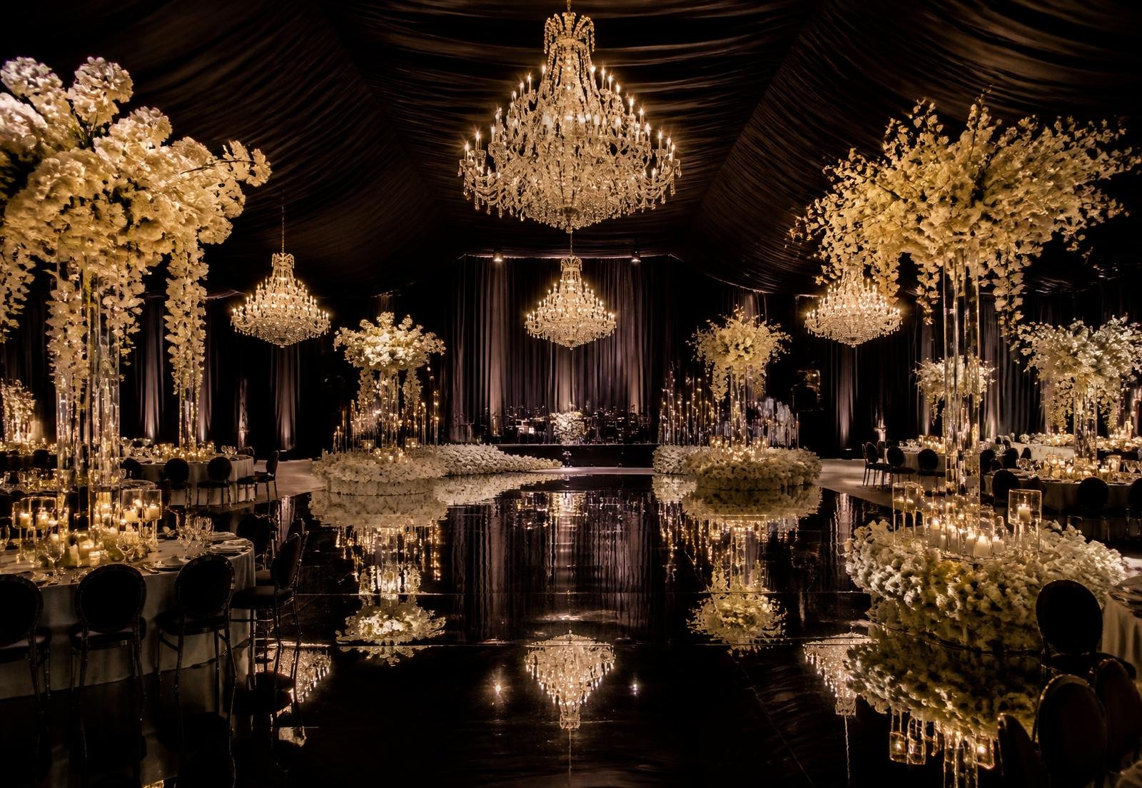 Grand wedding reception with tall ivory floral installations and chandeliers